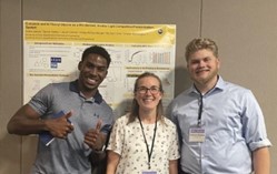Three people pose with a research poster