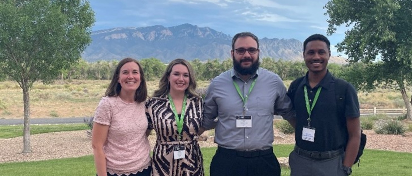 Four people posing for a photo outside